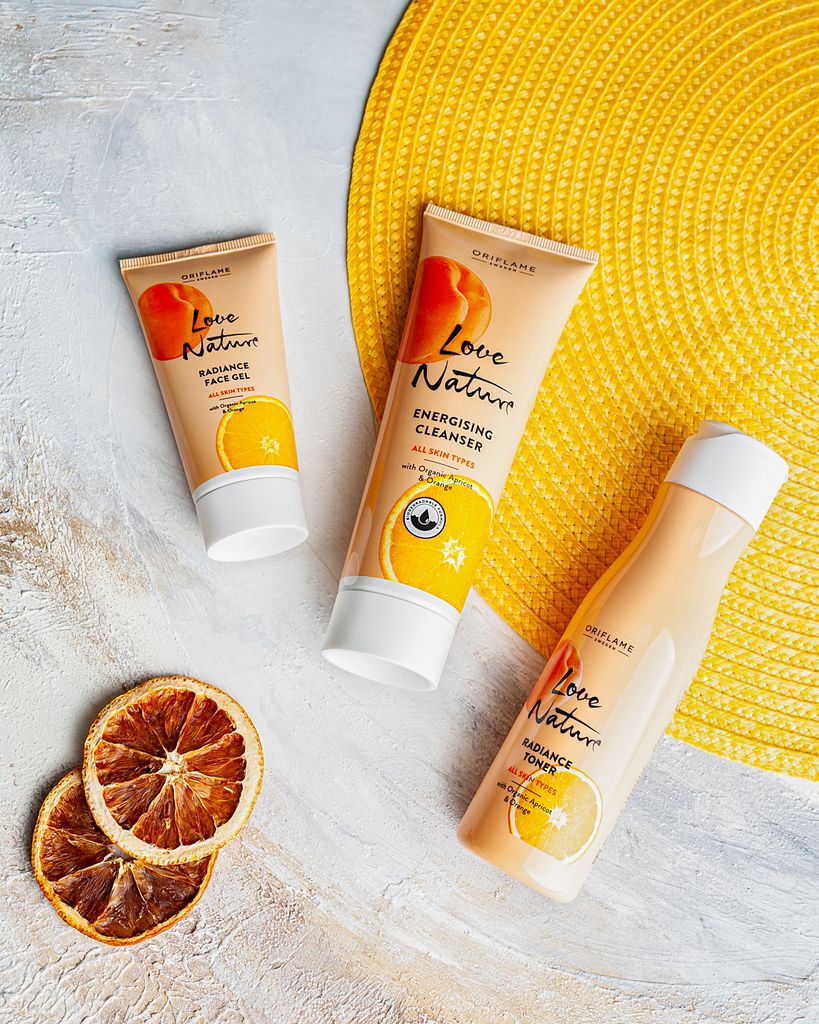 Citrus-themed skincare products arranged creatively on a textured surface with sliced oranges.